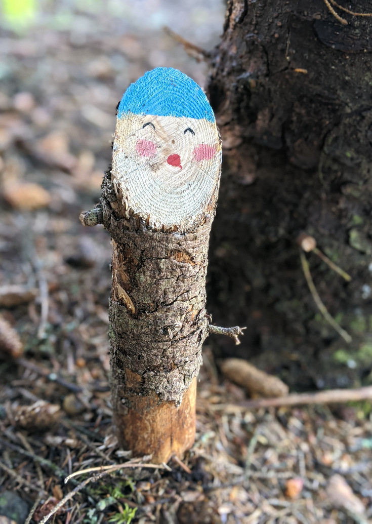 Painted dwarf with a blue hat peeking from bark
