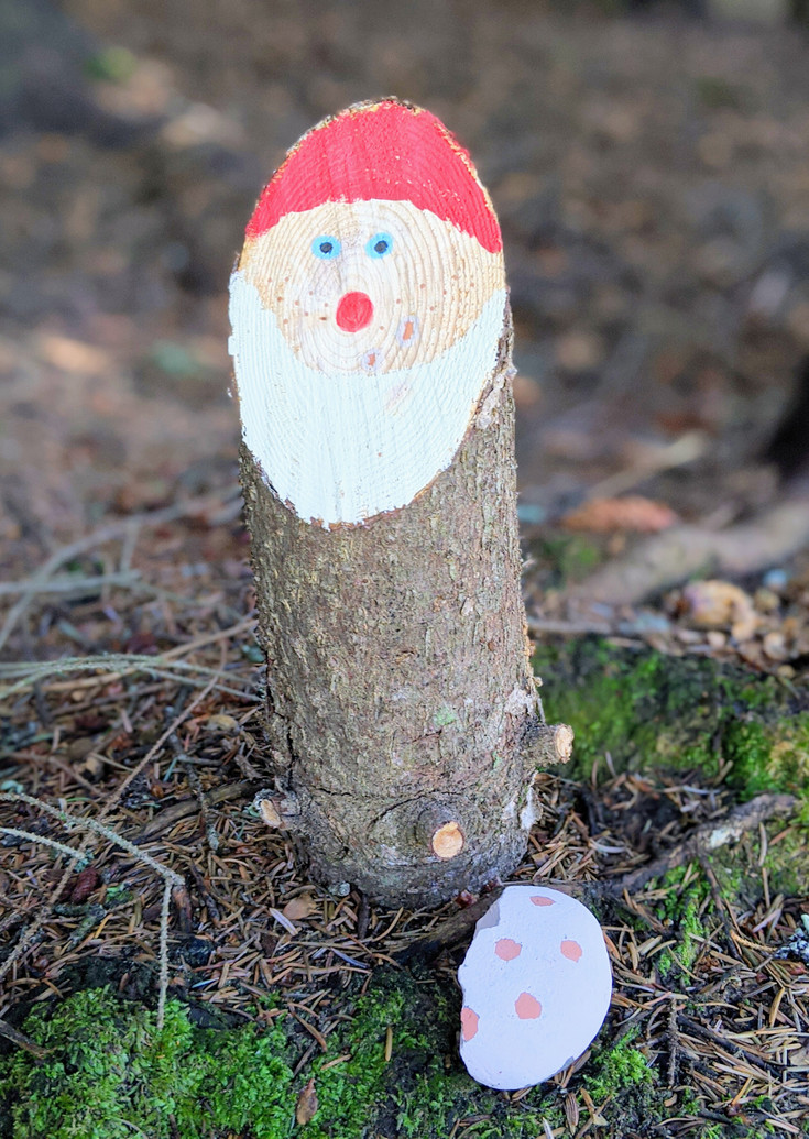 Painted dwarf with a red hat on a tree trunk